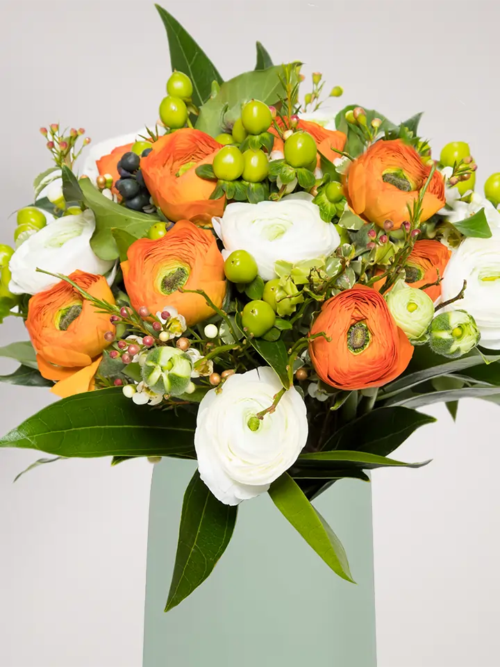 Bouquet ranuncoli arancio e bianchi e bacche verde close up